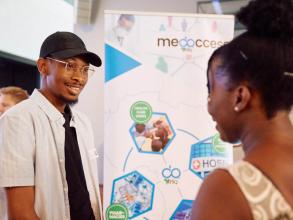 Medaccess founder stood next to his stand chatting to a Demo Night attendee