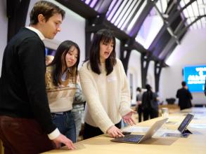 Two women showing a digital business model canvas on a laptop to a man