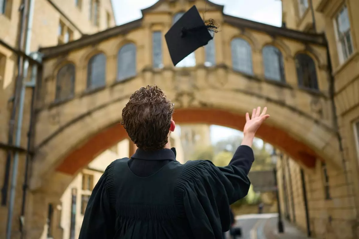 STUDENT CELEBRATING THE END OF AN EXAM BY TOSSING HIS MORTAR BOARD