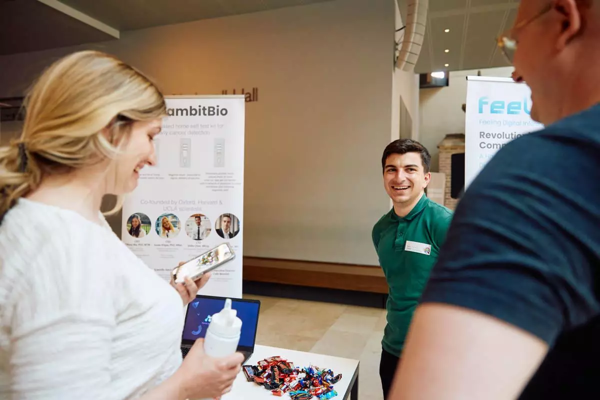A GambitBio founder standing next to his stand chatting to Demo Night event attendees