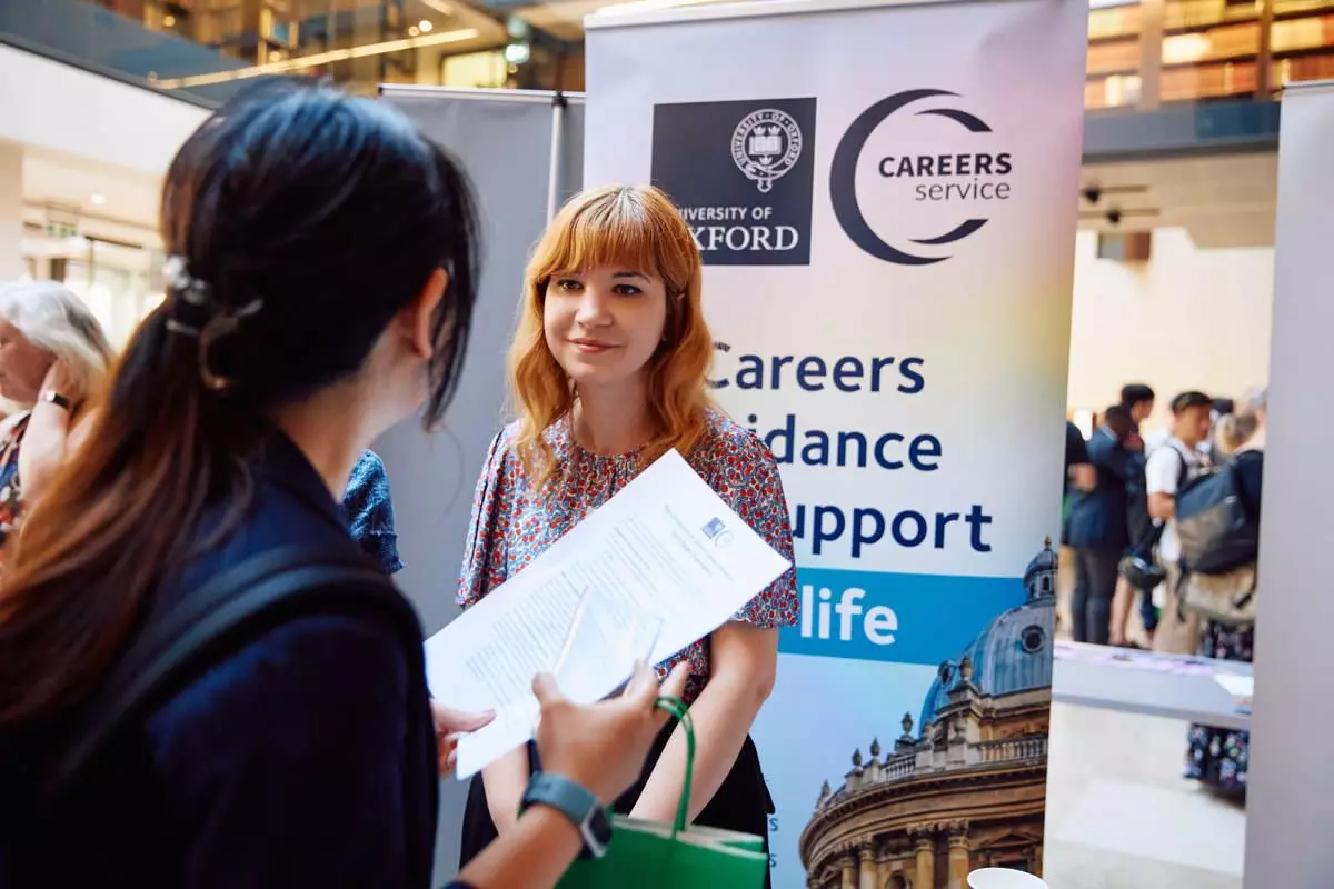 A woman stood at a Careers service stand talking to someone at an event