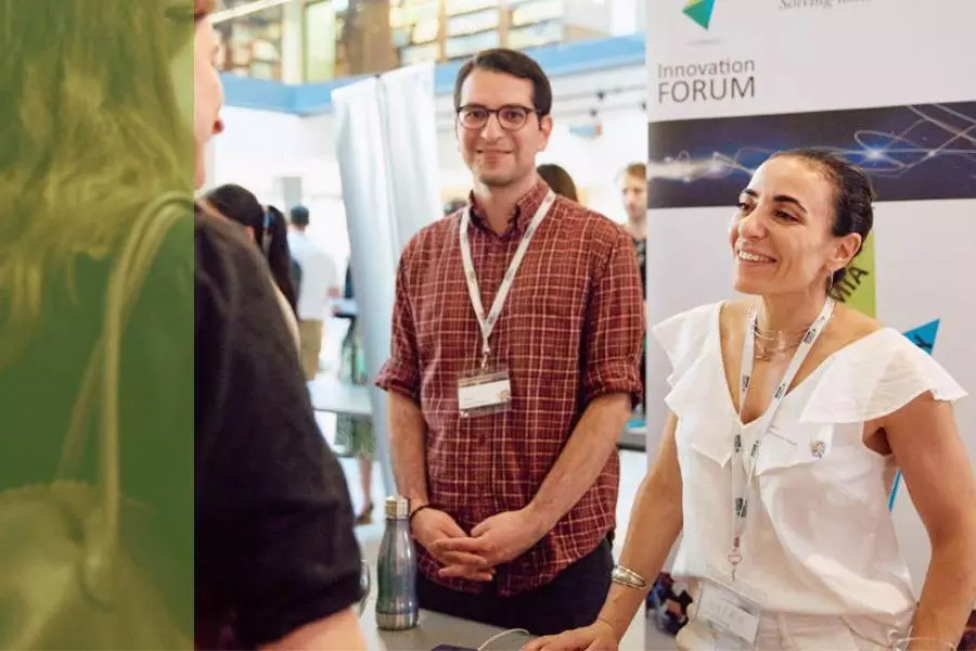 A man and a woman from a community innovation team chatting to an event attendee
