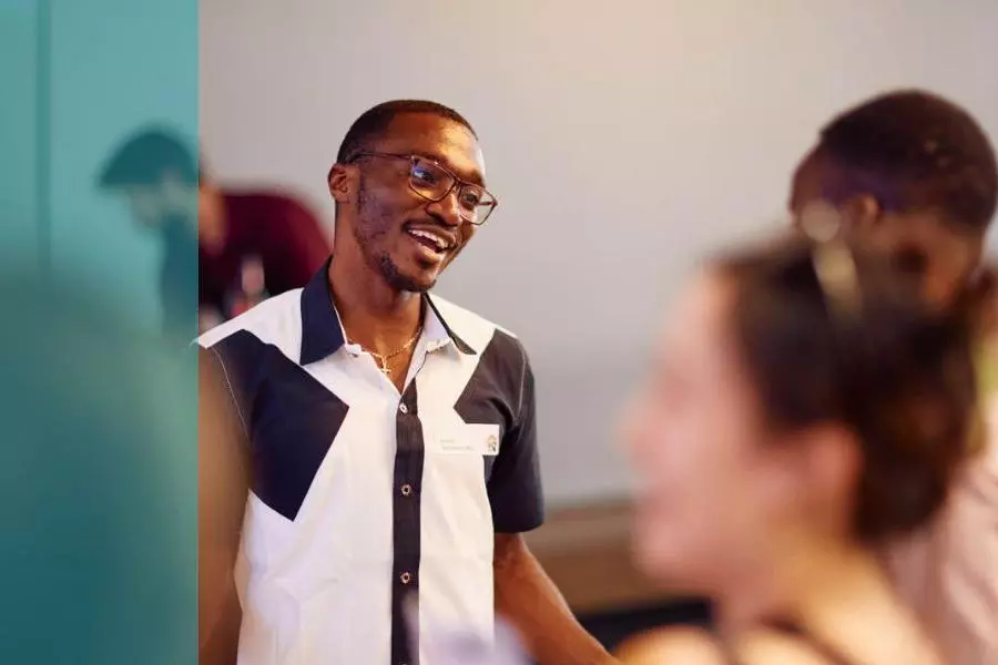 A man smiling and talking to someone at an event