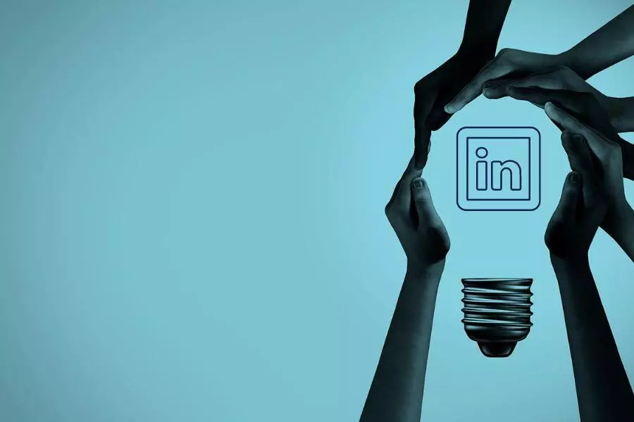 Multiple hands positioned to make the shape of a lightbulb with a linkedin icon in the middle