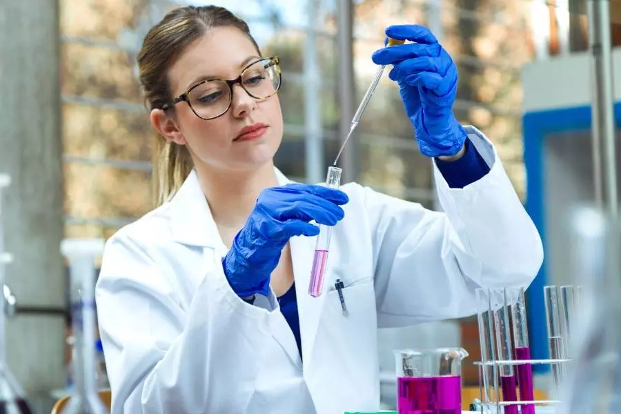 A female scientist in a lab holding up a pipette and test tube